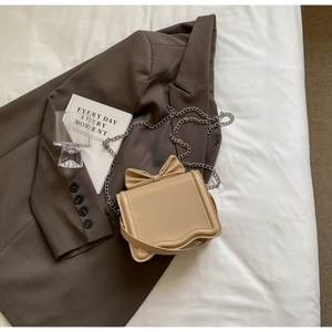 Close-up of khaki crossbody bag featuring a bow accent and elegant wavy flap design
