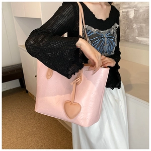 Detail of pink tote bag with pleated leather texture and a heart-shaped charm accessory