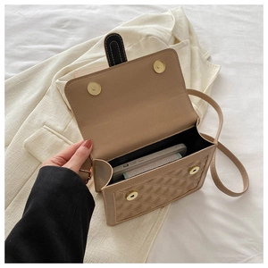 Macro shot of beige quilted crossbody bag interior showing magnetic buckles and phone capacity