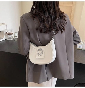 Detailed view of white crescent bag with sparkling crystal buckle on casual shoulder wear