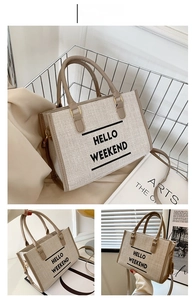 Detail view of khaki canvas tote bag with HELLO WEEKEND text and leather handles