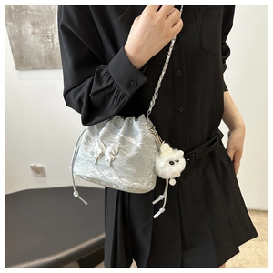 Close-up of a silver bucket bag with a butterfly buckle and white fuzzy monster charm