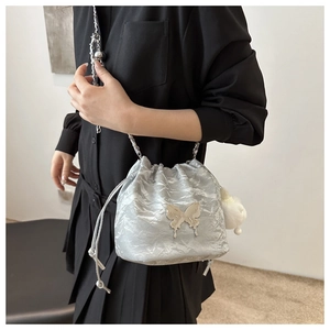 Detail of silver pleated bucket bag with butterfly metal ornament and chain strap