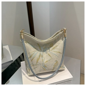 Detailansicht der beige Leinentasche mit eleganten Goldblatt- und Vogelstickereien
