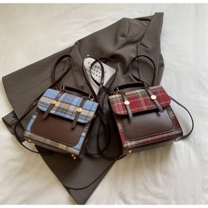 Detail view of vintage British style plaid backpacks with leather trim and gold buckles