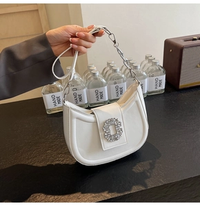 Detail of white crescent bag with sparkling crystal buckle and silver chain strap
