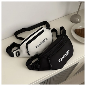 Flat lay of black and white nylon crossbody bags with FANYISSA text in a lifestyle setting