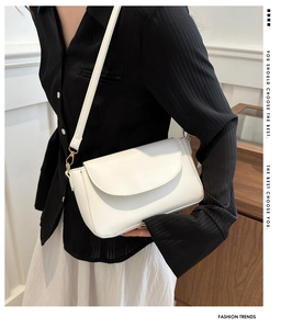 Detail of white PU leather crossbody bag featuring gold buckle and adjustable strap