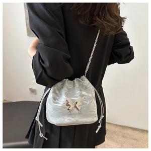 Silver pleated bucket bag with metallic butterfly detail and chain strap on model