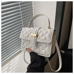 Close-up of white quilted leather texture and gold H-shaped buckle on small square bag