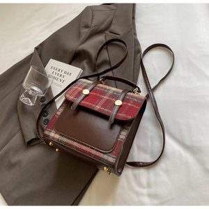 Detail of British style checkered backpack with brown leather flap and gold buckles