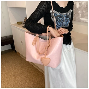 Close-up of pink tote bag with heart charm showing textured faux leather and large capacity