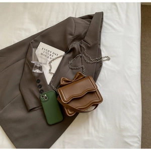 Detailed view of brown PU leather crossbody bag with bow decor and wavy flap design