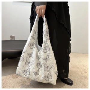 Close-up of white canvas tote bag with butterfly print and frayed fringe texture detail