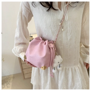 Pink drawstring bucket bag with gold corners and a cute cloud plush charm on a model