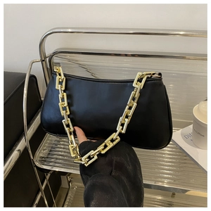 Détail du sac sous le bras en similicuir noir avec grosse chaîne dorée et fermeture éclair