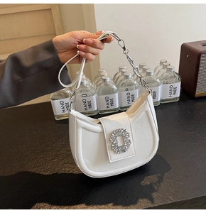 Detail of white half-moon underarm bag with sparkling crystal buckle and chain strap
