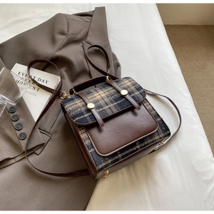 British style checkered backpack with brown leather trim on a minimalist white background