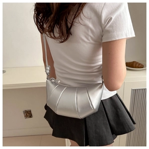 Détail du sac croissant argenté avec bandoulière nouée et texture en cuir plissé