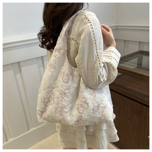 Close-up of a white tote bag featuring pink butterfly patterns and soft lace textures