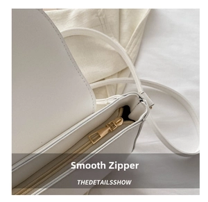 Detail of high-quality smooth golden metal zipper on a white matte leather shoulder bag
