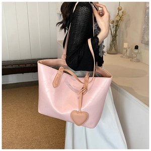 Close-up of pink pleated leather tote bag with heart charm and shoulder straps