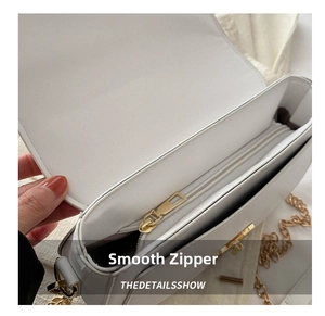 Detail of smooth golden zipper and hardware on white leather crossbody bag
