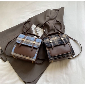 Detail of vintage plaid backpacks with leather trim and gold metal studs on a fabric background