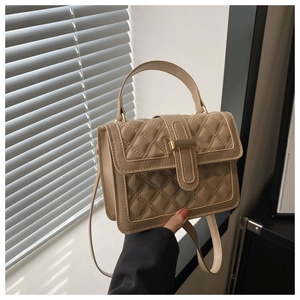 Macro shot of khaki quilted crossbody bag with gold hardware and top handle strap