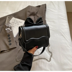 Detail of black bow square bag showing the wavy edge and metallic silver chain strap