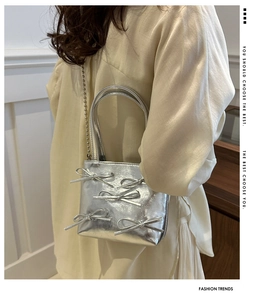 Silver metallic mini bag with bow detail and ball chain strap worn by a model