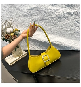 Detail of bright yellow patent leather baguette bag featuring a silver square buckle
