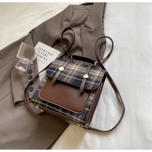 Detailed top view of vintage plaid backpack with faux leather and gold buckles on white fabric