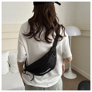 Detail of black nylon chest bag with adjustable strap and white FANYISSA print on model