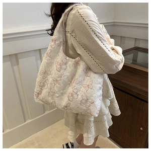 Detail of pink butterfly embroidery on white lace canvas tote bag with fringe texture