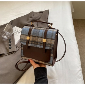 Detail of vintage plaid backpack with brown leather trim and golden metal buckles