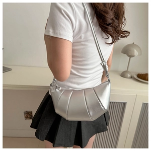 Détail du sac croissant argenté plissé avec bandoulière nouée porté par un mannequin