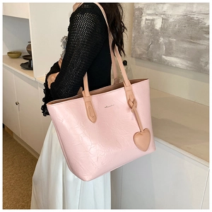 Detail of light pink pleated tote bag with heart charm shown on shoulder