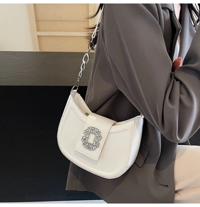 Detail of white leather shoulder bag with a sparkling crystal buckle and silver chain