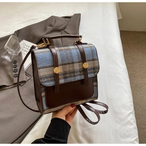 Detail of British style checkered backpack with brown leather trim and metal buckles