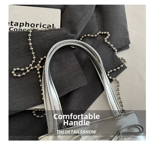 Close-up of silver mini tote bag with bow detail and metallic bead chain strap