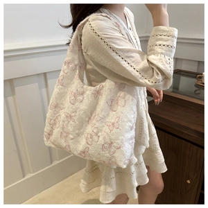 Detailed texture of white plush tote bag with delicate pink butterfly embroidery