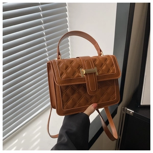 Detail of quilted brown faux leather bag featuring a gold rectangular metal push-lock