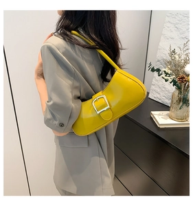Close-up of bright yellow patent leather shoulder bag with a large silver buckle detail