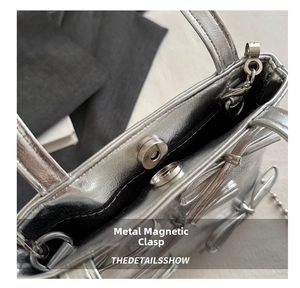 Detail shot of the silver metallic bucket bag showing its premium hardware magnetic snap closure