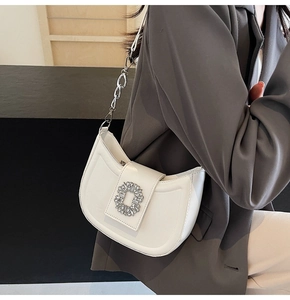 Detail of elegant white crescent bag with silver rhinestone buckle and metal chain