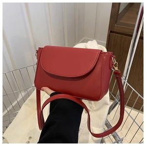 Detail of red matte leather crossbody bag with metal hooks and adjustable strap