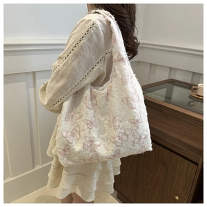 Detail of white chiffon tote bag featuring pink butterfly embroidery and textured fabric