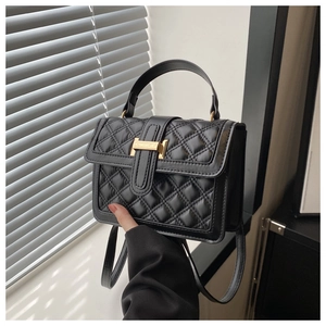 Detail of black quilted leather handbag with gold H buckle shown in natural light