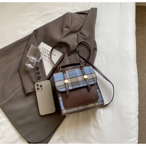 Detail of British style checkered backpack with brown leather accents and gold hardware